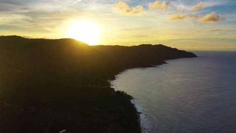 tranquil sunrise drone shot of the caribbean sea near st. croix, with soft clouds, a warm orange sky, and a peaceful peninsula surrounded by still water and morning mist