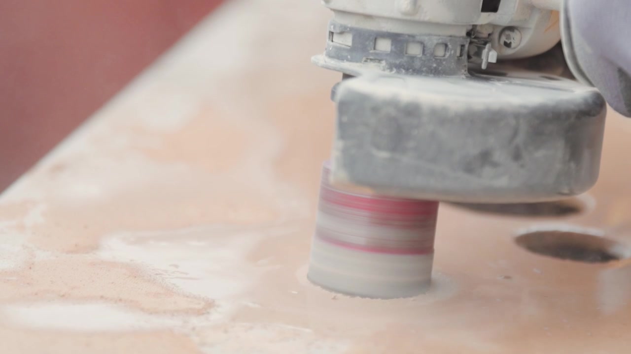 Close up of a power tool cutting holes in a ceramic tile. Circular cutter.