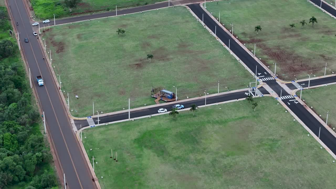 Static aerial shot of housing lots ready for construction in Posadas, Misiones, Argentina, showing paved roads, sidewalks, and a central shelter surrounded by undeveloped grassy land