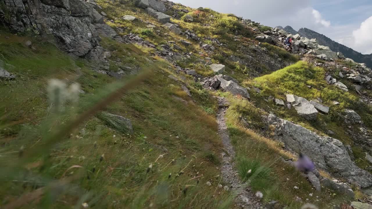 plano general de un excursionista masculino caminando por un camino rocoso en la montaña durante el día soleado