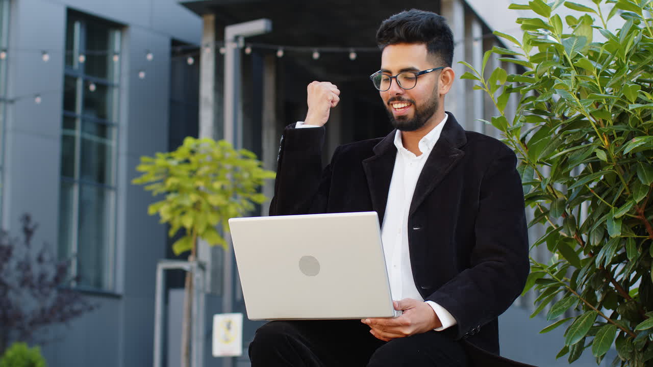 Businessman working on laptop reading good news, rejoicing success, celebrate online win victory