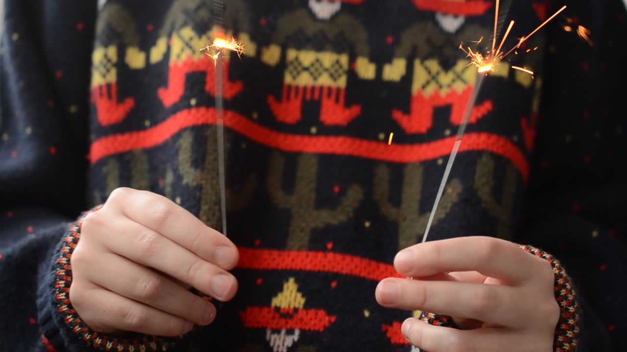 Dívka drží v ruce prskavku. Nový rok a Vánoce