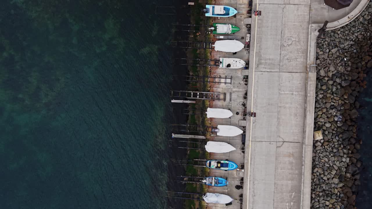 Boats lined up at a marina during midday near the water