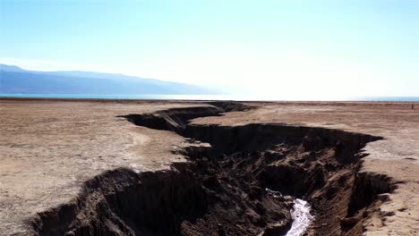 large sinkhole in arid landscape leading to the dead sea