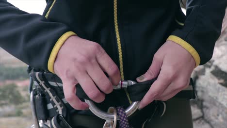 female rock climber closing a carabiner securing it before climbing