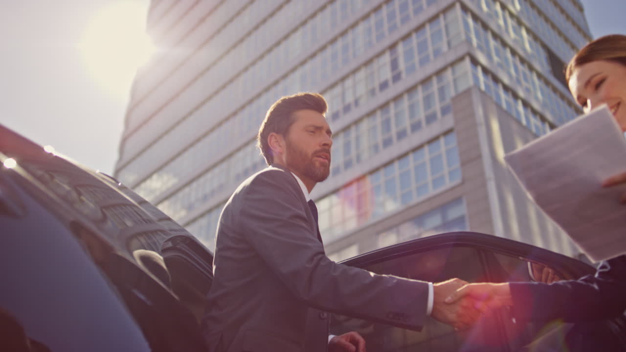Businesswoman meeting business partner getting out luxury car to sunny street.