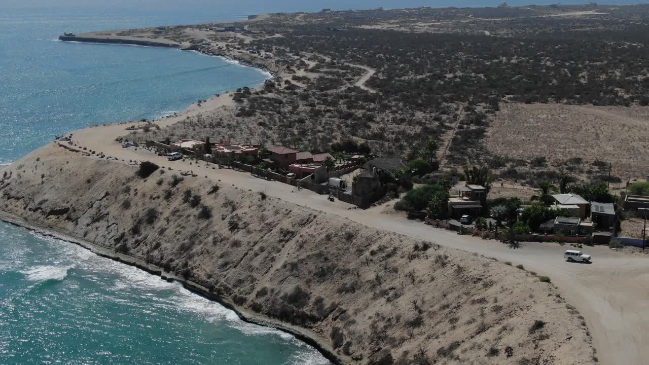 vista aérea moviéndose hacia adelante, un camión cruzando la carretera arenosa de san juanico, california sur, méxico, pastizales secos en el fondo