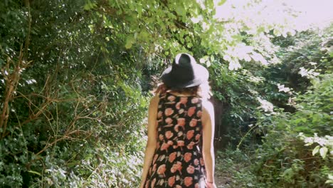 young woman walks down a narrow path through a dense wood