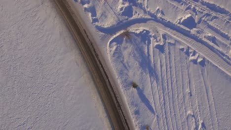 snowy road with tire tracks from aerial view