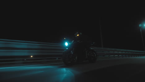 a man rides a sports motorcycle through the city at night