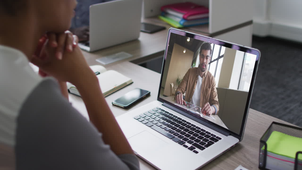African american woman having a video conference on laptop with male office colleague at office