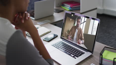 mujer afroamericana teniendo una videoconferencia en una computadora portátil con un colega de oficina masculino en la oficina