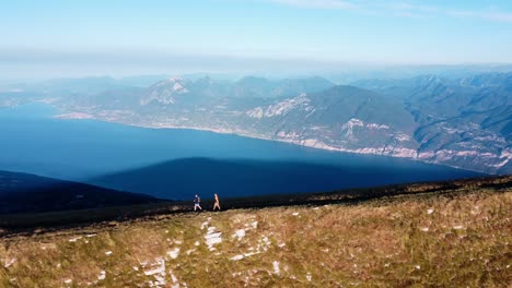 2 hikers walking on the top of the monte baldo with view on lake garda