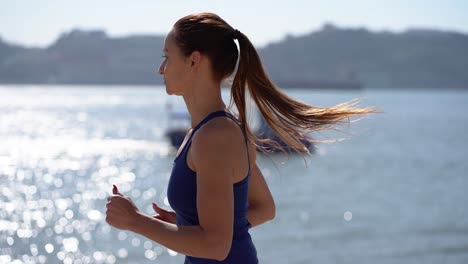 beautiful young sportswoman running at riverside