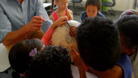 caucasian male teacher teaching his kids about globe in classroom 4k