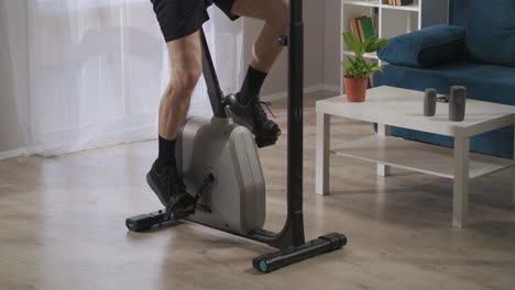 home training with spinning bike closeup view of male legs on pedals sport and physical activity at middle and old age