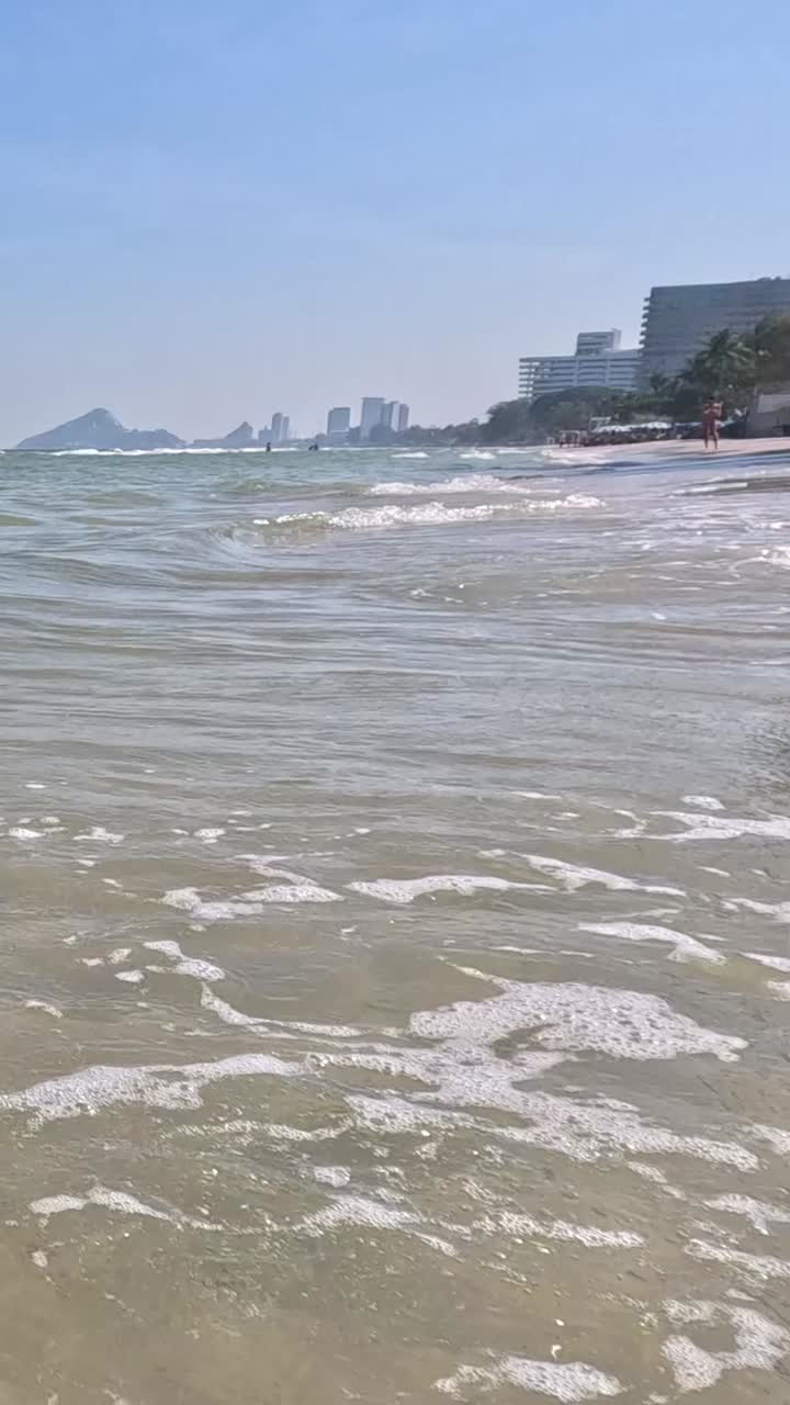 Beach scene with waves and buildings in the background