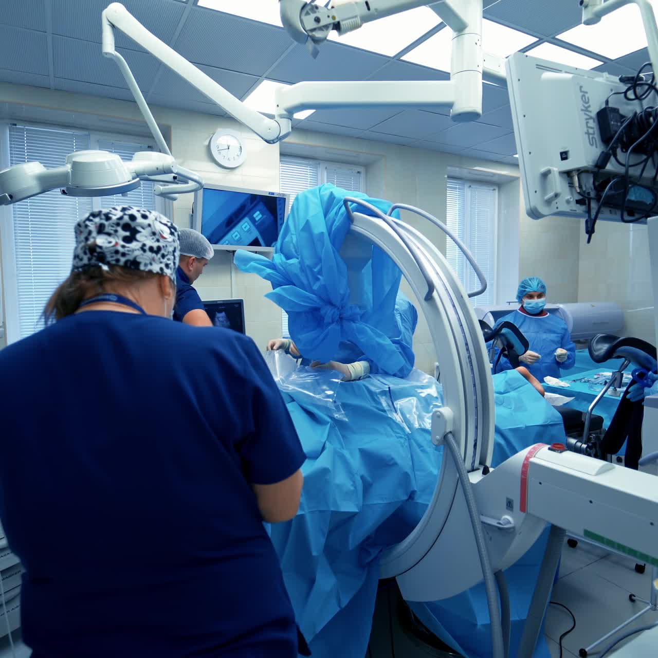 Medical specialists in modern operating room. Doctors perform a surgery and looking on the process on the monitor
