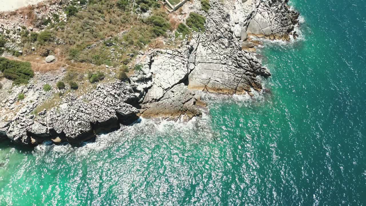 Албания: синие воды Ионического моря и пенящиеся волны, разбивающиеся о скалистый берег