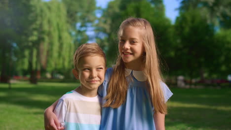 una niña sonriente abraza a su hermano pequeño mirando a la cámara. un niño no está dispuesto a abrazarlo.