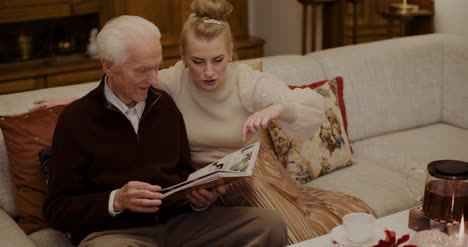 granddaughter looking at photo album with grandfather 1