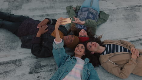 happy friends hanging out lying on rooftop taking selfie photo using smartphone camera enjoying sharing weekend together