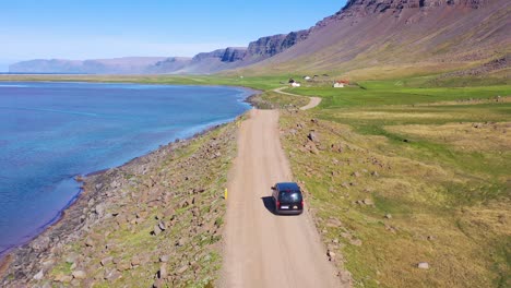 aerial over a black van traveling on a dirt road in iceland near raudisandur beach in the northwest fjords 4