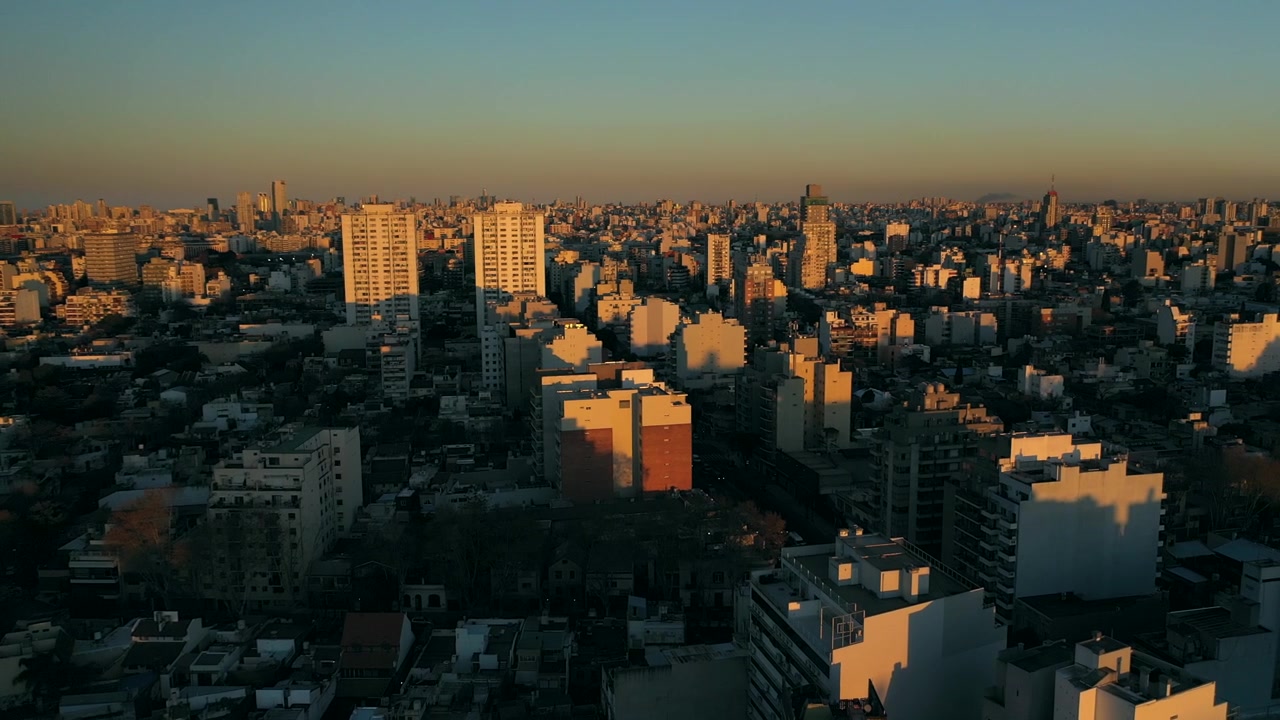 Drone: Tramonto sulla città. Ora d'oro su edifici e torri. Movimento in avanti. Lento.