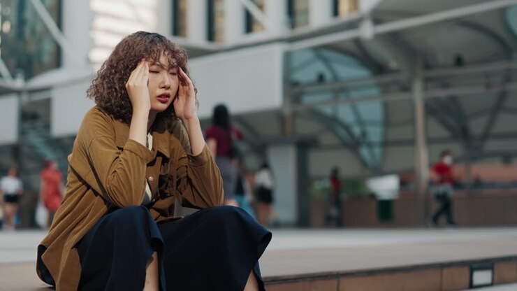Woman with Headache Sitting on Steps in City