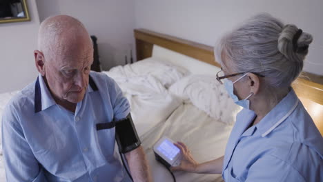 nurse checking senior man's blood pressure