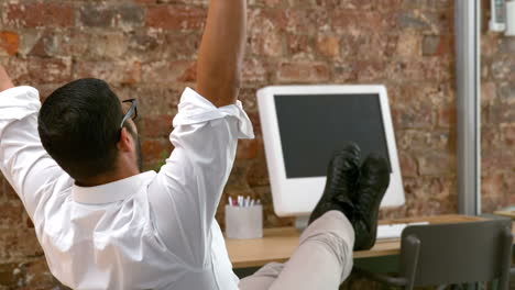 Casual-businessman-relaxing-at-desk-leaning-back