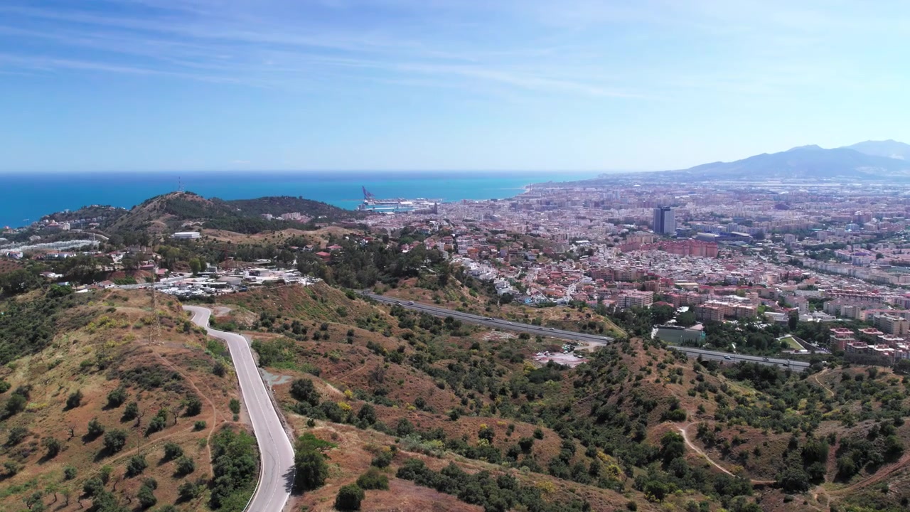 Widok z lotu ptaka na miasto Malaga i otaczające wzgórza, powoli przesuwający się na boki i pochylający się w górę, Andaluzja, Hiszpania.