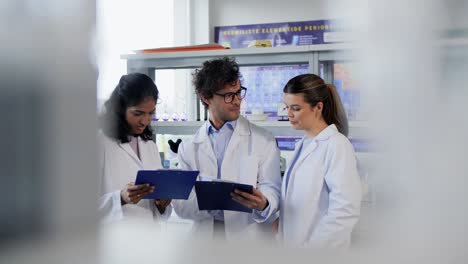 International-Group-of-Scientists-in-Laboratory.science-research,-work-and-people-concept-international-group-of-happy-scientists-with-clipboards-discussing-report-in-laboratory