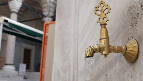 close-up of a brass water fountain in a mosque courtyard