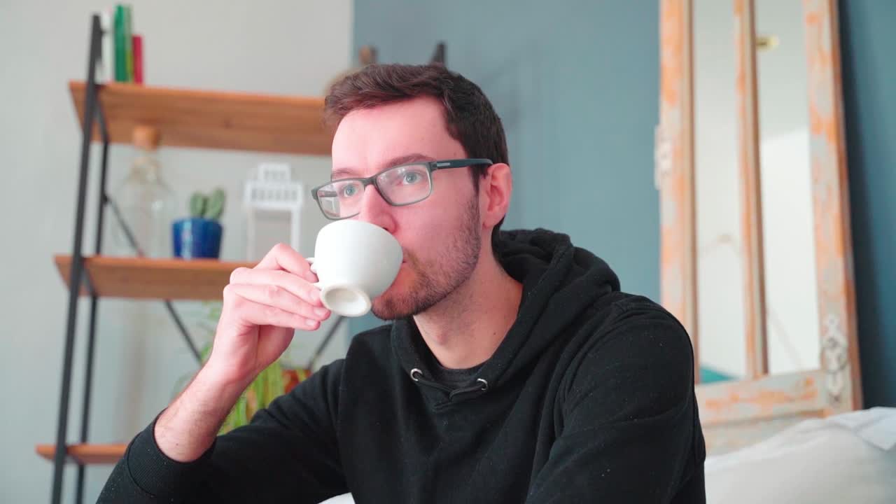 joven bebiendo café espresso sentado en el sofá en casa