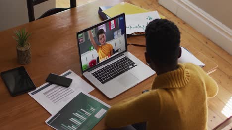 African-american-female-teacher-talking-and-taking-notes-while-having-a-video-call-on-laptop-at-home