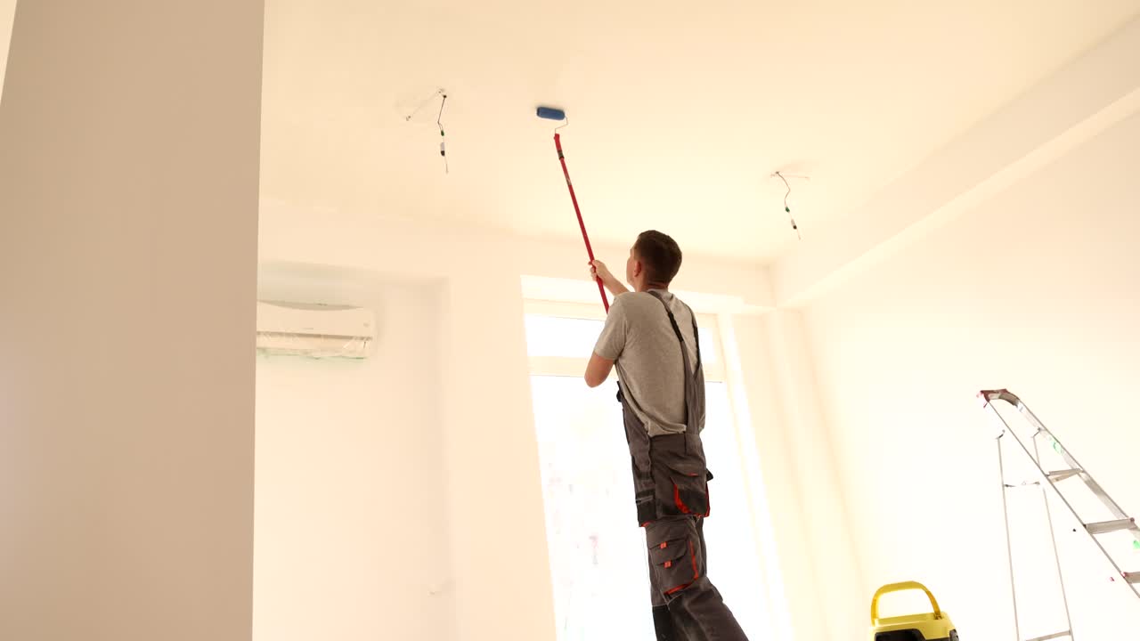 Man Painting Ceiling in a Room