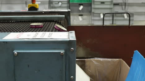 factory worker checking the aluminum caps moving on the conveyor to the box at factory