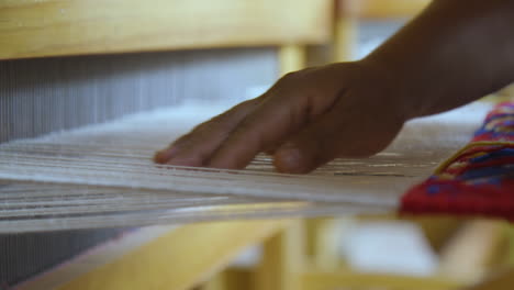 a women weaving blue wool on a loom to create a tapestry