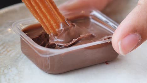 person dipping churros in chocolate