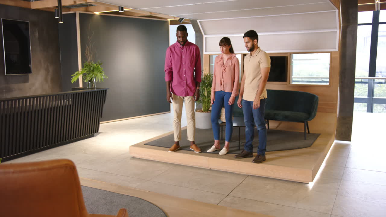 Discussing work, three diverse colleagues standing together in modern office