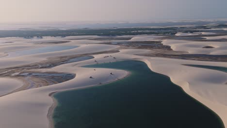 aerial drone descending shot view over the white sand dunes and crystal clear freshwater lagoons of the lencois maranhenses in maranhao, brazil. unesco world heritage site. establishing shot. desert