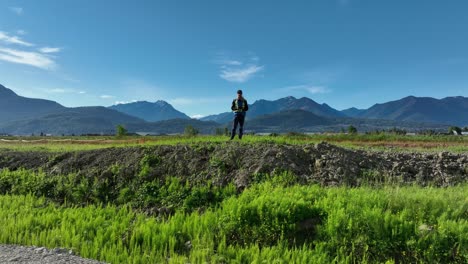 Drone-Pilot-Standing-And-Holding-Remote-Control,-Controlling-Drone-Ascending-From-The-Ground