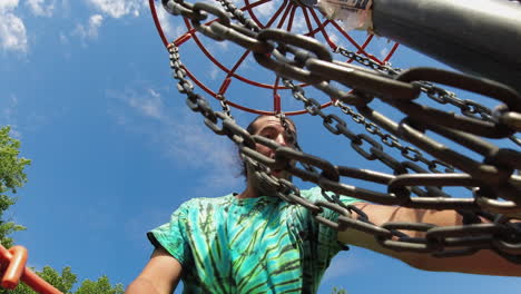 a unique inside-the-basket view of a man celebrating a successful disc golf shot, capturing his joyful reaction against a backdrop of blue sky and chains