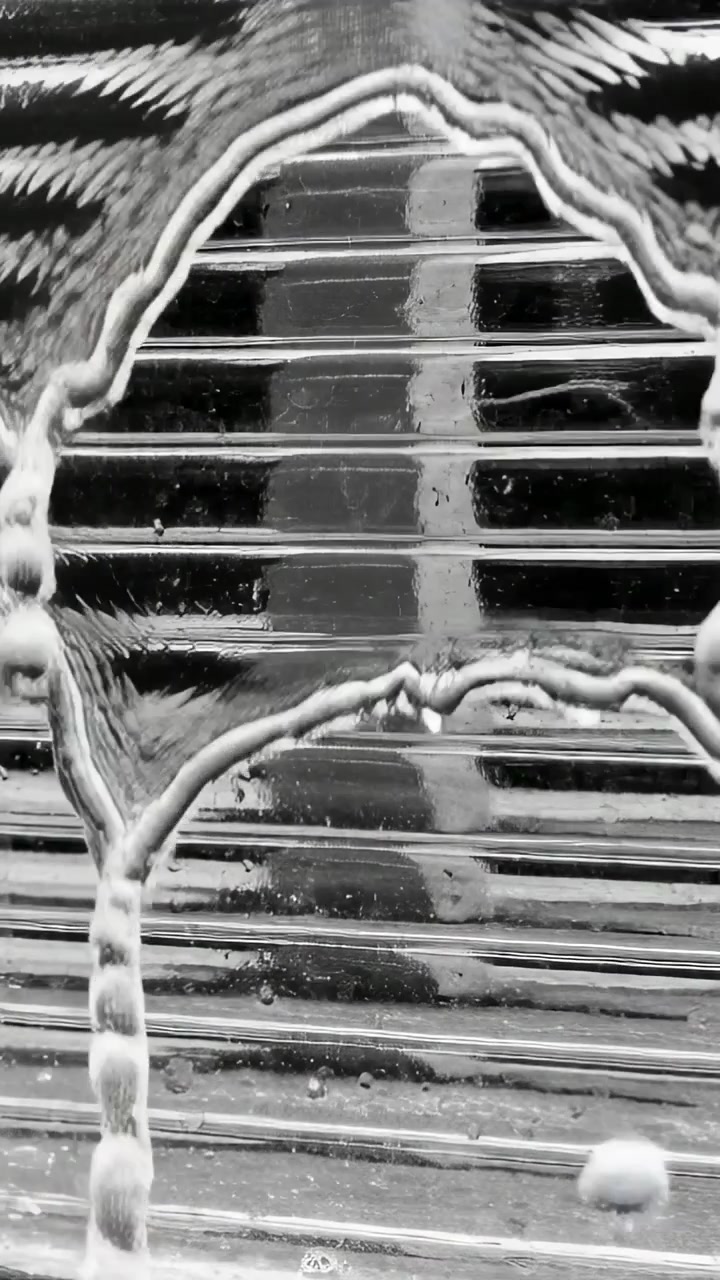 Video verticale: Goccioline che scivolano per gravità formando perle su un pannello scanalato, colonna che si deforma, lamelle.