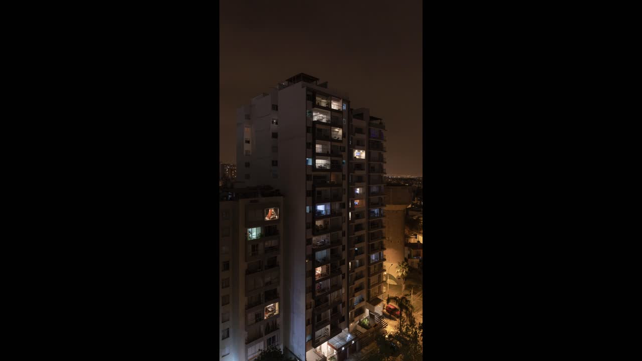 Alto condominio con finestre illuminate di notte.