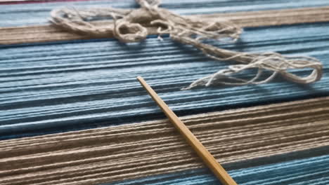 weaving board with strands of yarn and weaving needle on it, dolly out view