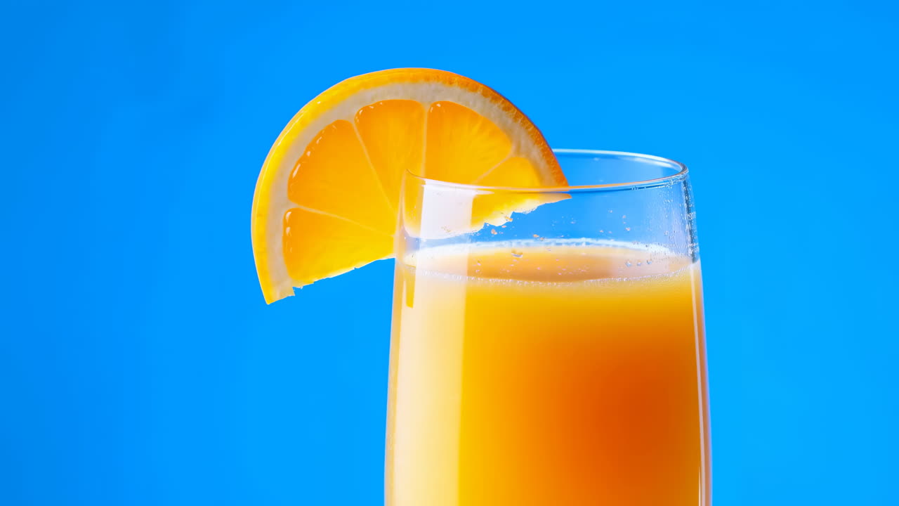 Glass of Orange Juice with Orange Slice on Blue Background