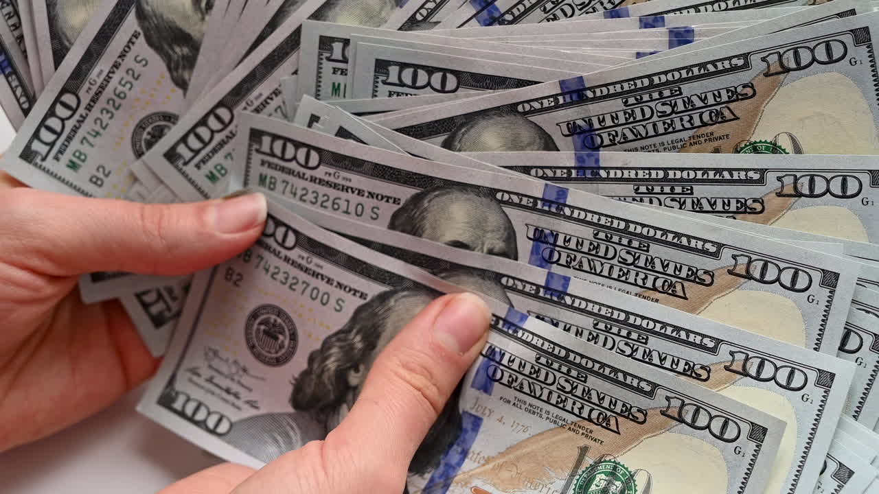 Close up of female hands holding a wide fan of one hundred dollar bills