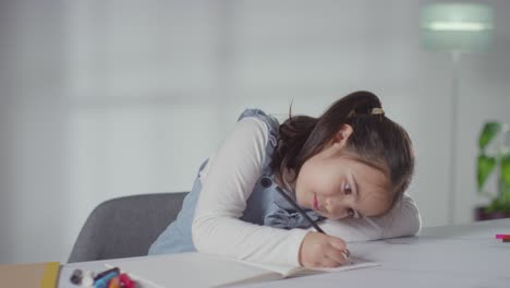 young girl on asd spectrum at table at home concentrating on writing in school book